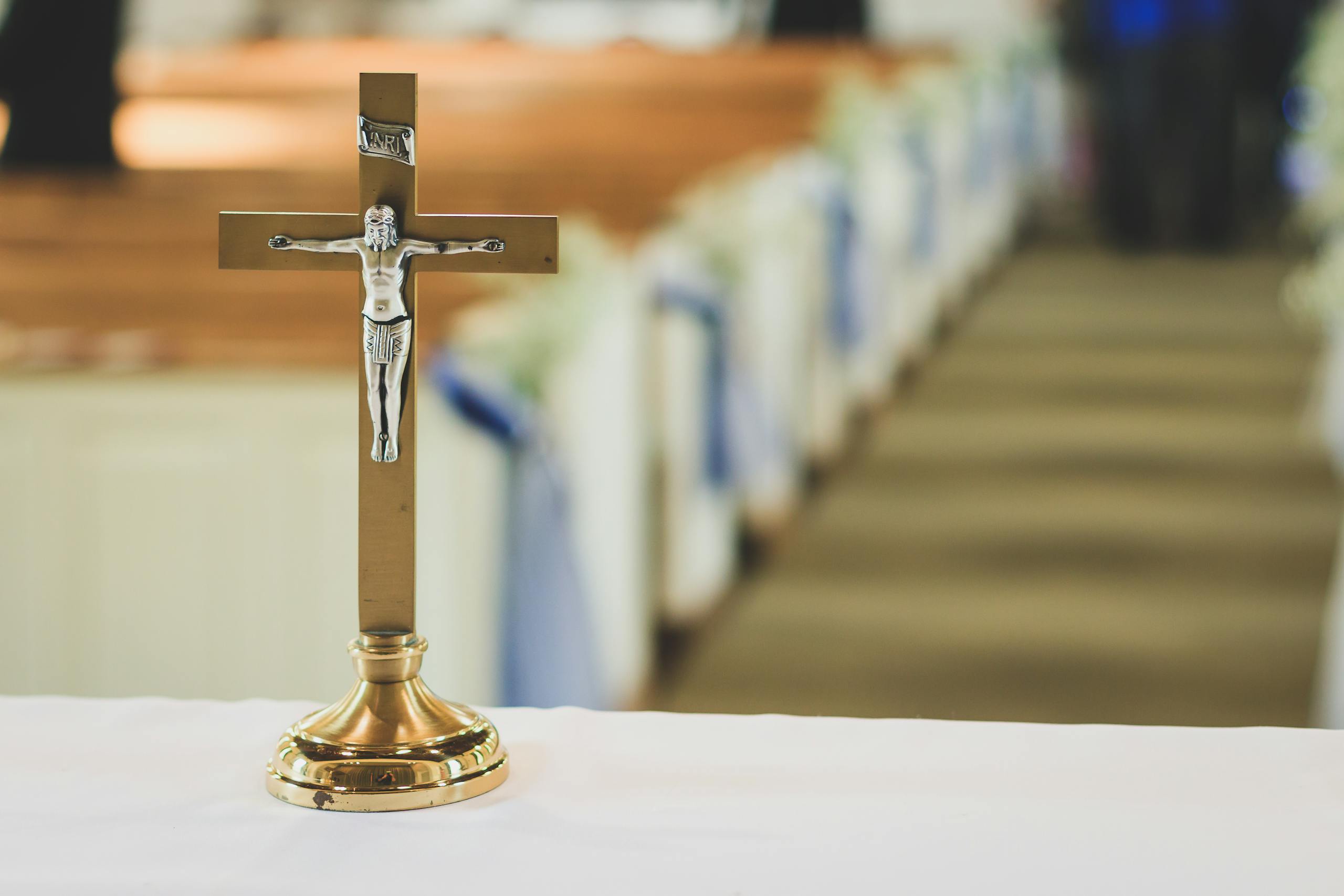 A gold crucifix on an altar with blurred church pews in the background.