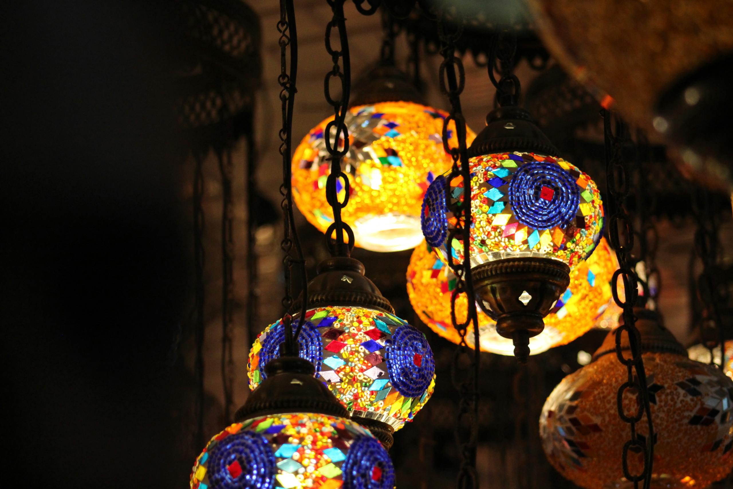 Colorful mosaic glass lamps hanging in a Dhaka market, illuminating the space with warmth.