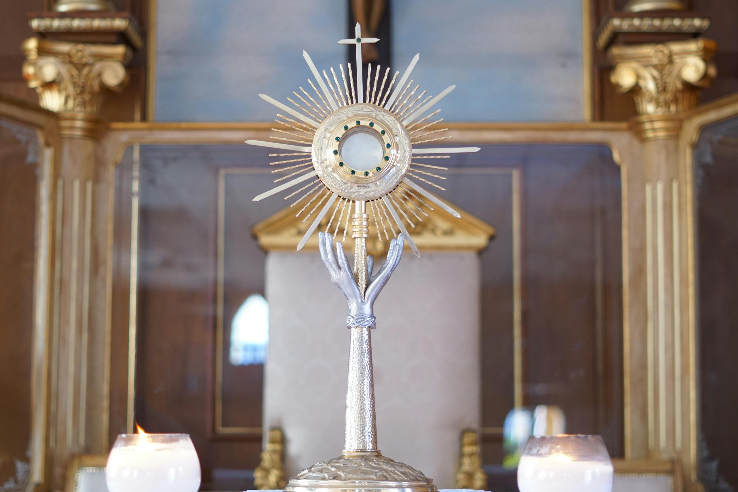 Close-up of a gold monstrance with candles symbolizing religious significance in a church.